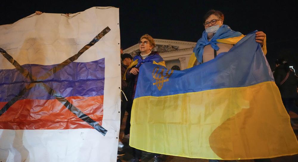 Người dân Ukraine giơ cao quốc kỳ của đất nước họ khi họ tham dự một hành động yêu nước “Mariupol là của Ukraine” ở Mariupol, Ukraine, Thứ Ba, ngày 22 tháng 2 năm 2022 (Ảnh: Sergei Grits / AP)