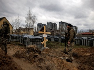 Những người lính Ukraine đứng cạnh ngôi mộ của một thường dân ở Bucha, Ukraine, ngày 6 tháng 4 năm 2022. Cư dân địa phương cho biết người dân này đã bị lính Nga giết trong cuộc xâm lược Ukraine (Ảnh: Alkis Konstantinidis / Reuters qua CNS)