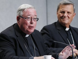 Đức Hồng Y Jean-Claude Hollerich Địa phận Luxembourg, Tổng tường trình viên của Thượng Hội Đồng Giám Mục, phát biểu tại một cuộc họp báo để trình bày cập nhật về Tiến trình Hiệp hành tại Vatican ngày 26 tháng 8 năm 2022. Phía sau là Đức Hồng Y Mario Grech, Tổng thư ký của Thượng hội đồng (Ảnh: Paul Haring / CNS)