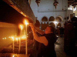 Một người phụ nữ thắp nến trước buổi lễ bắt đầu mùa Giáng sinh tại Nhà thờ Chúa Giáng Sinh ở Bethlehem, Bờ Tây, ngày 26 tháng 11 năm 2022. Trong thông điệp Giáng sinh của họ, các Thượng phụ và những người đứng đầu các Giáo hội tại Thánh Địa đã so sánh đau khổ của những người tị nạn với đau khổ của Thánh Gia (Ảnh: CNS /Mussa Qawasma, Reuters)