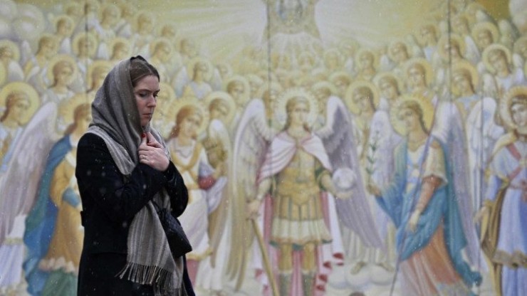 Một người phụ nữ đi ngang qua những bức bích họa trên bức tường bên ngoài Tu viện Mái vòm Vàng Thánh Michael ở Kiev vào ngày 25 tháng 12 năm 2022, trong bối cảnh Nga xâm lược Ukraine (Ảnh: AFP)