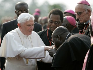 Một giáo sĩ châu Phi hôn nhẫn Đức nguyên Giáo hoàng Bênêđictô XVI khi ngài đến sân bay ở Yaounde, Cameroon, thứ ba, ngày 17 tháng 3 năm 2009 (Ảnh: AP Photo/Rebecca Blackwell)