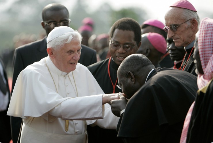 Một giáo sĩ châu Phi hôn nhẫn Đức nguyên Giáo hoàng Bênêđictô XVI khi ngài đến sân bay ở Yaounde, Cameroon, thứ ba, ngày 17 tháng 3 năm 2009 (Ảnh: AP Photo/Rebecca Blackwell)