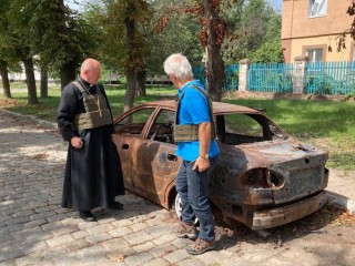 Đức Giám mục phụ tá Jan Sobilo Địa phận Kharkiv-Zaporizhia, Ukraine, bênh cạnh một chiếc xe bị phá hủy vào mùa hè năm 2022 ở khu vực phía đông Ukraine do Giáo phận quản lý (Ảnh: OSV News/do Đức Giám mục Sobilo cung cấp)
