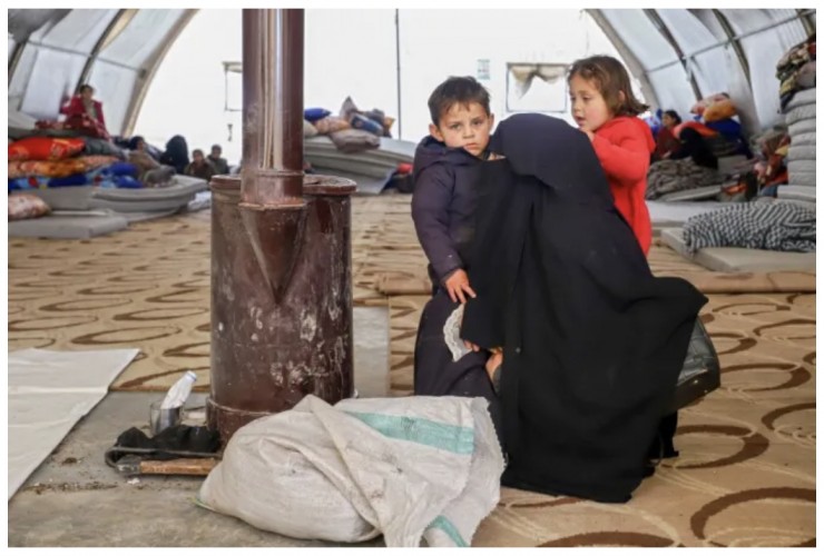 Một phụ nữ Syria và các con sưởi ấm bên bếp lò tại một nơi trú ẩn khẩn cấp ở trung tâm thành phố Maarat Misrin, thuộc khu vực do quân nổi dậy chiếm giữ ở phía bắc của tỉnh Idlib, tây bắc, ngày 7 tháng 2 năm 2023, một ngày sau trận động đất chết người tấn công Syria và Thổ Nhĩ Kỳ (Ảnh: ABDULAZIZ KETAZ/AFP via Getty Images)