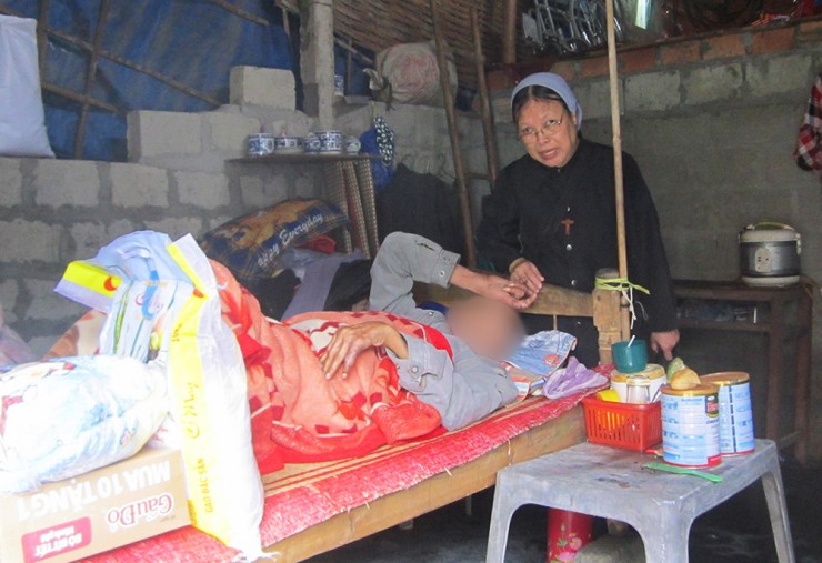 Nữ tu Lucia Nguyễn Thị Ngô FMI phát cơm, mì gói và sữa cho một bệnh nhân (được che mặt để bảo vệ danh tính) vào ngày 12 tháng 11 năm 2022, tại huyện Phú Lộc, Việt Nam (Ảnh: GSR/Joachim Phạm)