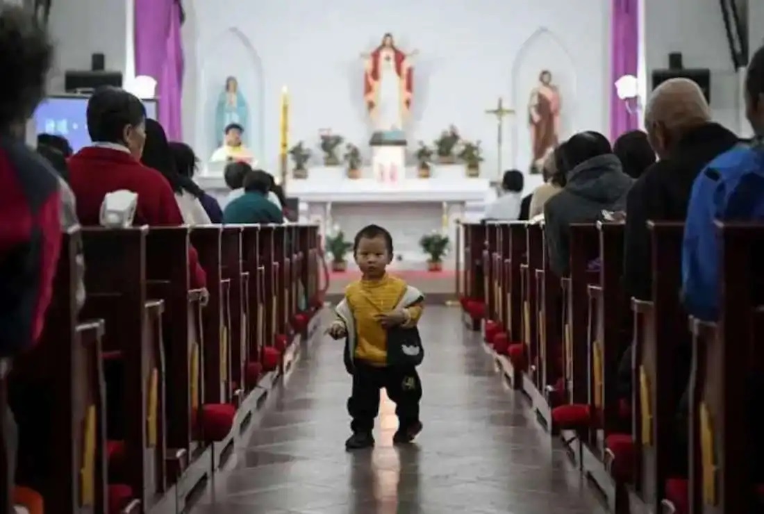 Một em bé Trung Quốc đi qua lối đi trong Thánh lễ tại một nhà thờ Công giáo ở một ngôi làng gần Bắc Kinh vào Thứ Bảy Tuần Thánh, ngày 3 tháng 4 (Ảnh: Jade Gao/AFP)
