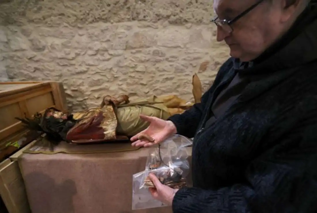 Một  Linh mục đang chỉ vào một phần của bức tượng Chúa Giêsu bằng gỗ đã bị kéo đổ và hư hại trong Nhà thờ Kết án, nơi các Kitô hữu  tin rằng Chúa Giêsu đã bị đánh đòn và bị kết án tử hình, tại Thành phố Cổ Giêrusalem vào ngày 2 tháng 2 năm 2023 (Ảnh: AFP )