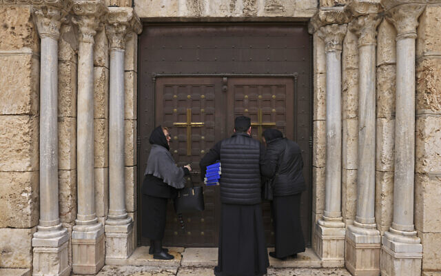 Một số giáo dân đứng bên cạnh một giáo sĩ bên ngoài lối vào đã đóng cửa dẫn vào ngôi mộ của Đức Trinh Nữ Maria tại Giêrusalem vào ngày 19 tháng 3 năm 2023 sau một vụ tấn công của người Israel - Giáo hội Chính thống giáo Hy Lạp tại Giêrusalem đã lên án vụ tấn công "tàn ác" diễn ra trong thánh lễ Chúa nhật tại Nhà thờ Gethsemane ở Giêrusalem, nơi có Mộ của Đức Trinh Nữ Maria (Ảnh: HAZEM BADER/AFP)