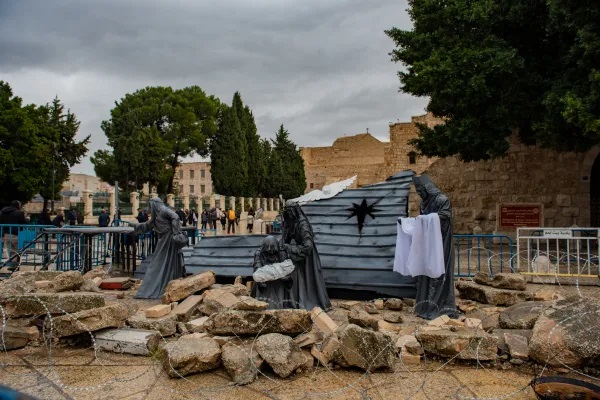Hang đá Chúa Siáng Sinh ở Bethlehem mô tả Thánh Gia được bao quanh bởi hàng rào thép gai và những mảnh vụn đổ nát của chiến tranh (Ảnh: Marinella Bandini/CNA)