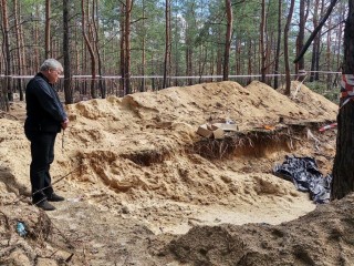 Đức Hồng Y Konrad Krajewski cầu nguyện tại một ngôi mộ tập thể ở Izyum, Ukraine, vào ngày 19 tháng 9 năm 2022. (Ảnh: Vatican Media.)