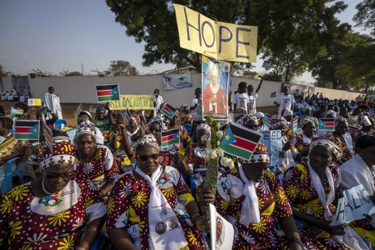 Những người phụ nữ cầm quốc kỳ và biểu ngữ hòa bình đang chờ đợi sự xuất hiện của Giáo hoàng Francis tại Nhà thờ St. Theresa ở Juba, Nam Sudan vào ngày 4 tháng 2 năm 2023. Kế hoạch tổ chức cuộc bầu cử đầu tiên vào tháng 12 của Nam Sudan sẽ đánh dấu một cột mốc quan trọng trong nỗ lực Để có được hòa bình lâu dài kể từ khi kết thúc cuộc nội chiến, bạo lực hàng loạt và các vi phạm nhân quyền trắng trợn kèm theo vẫn tiếp tục không suy giảm, một báo cáo của Ủy ban Nhân quyền Liên hợp quốc tại Nam Sudan cho biết. (Ảnh: Ben Curtis/AP)