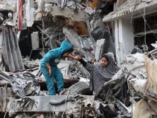 Một phụ nữ Palestine đang giúp một đứa trẻ chơi trên đống đổ nát của một tòa nhà bị phá hủy sau vụ ném bom trước đó của Israel ở Thành phố Gaza vào ngày 8 tháng 4 năm 2024, trong bối cảnh xung đột đang diễn ra giữa Israel và nhóm chiến binh Hamas của Palestine (Ảnh: AFP/ Getty Images)