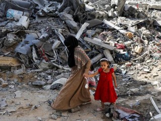 Một người phụ nữ và trẻ em đi giữa đống đổ nát ở trại tị nạn Nuseirat ở trung tâm Dải Gaza, ngày 9 tháng 6 năm 2024, sau các cuộc tấn công của Israel vào khu vực, nơi các con tin Israel được giải cứu, trong bối cảnh xung đột Israel-Hamas (Ảnh: OSV News/Abed Khaled, Reuters)