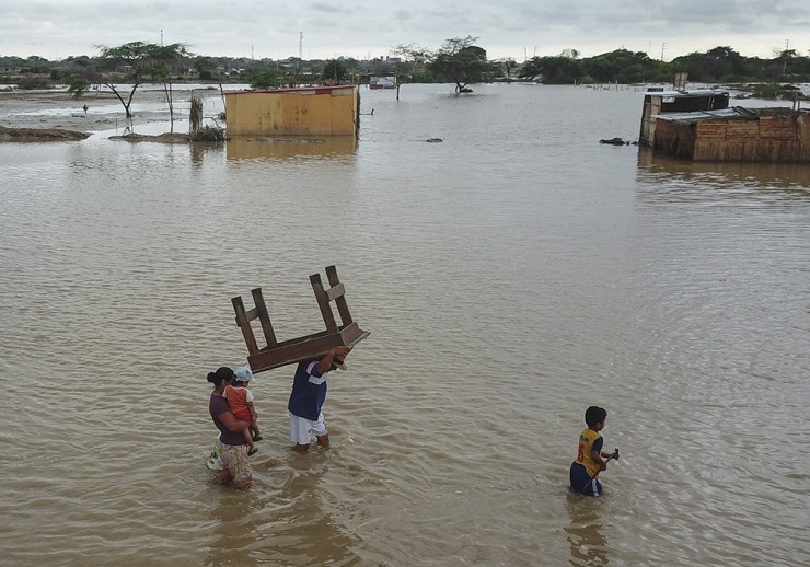 A man carries a table through a street flooded by heavy rains of Cyclone Yaku, in Chiclayo, Peru, Sunday, March 12, 2023. Cyclone Yaku is present in the South Pacific off the coasts of Peru and Ecuador, where it has affected some provinces in both countries. (AP Photo/Aldair Mejia)