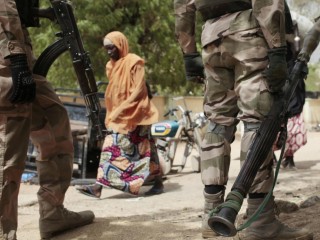 Một người phụ nữ đang bước ngang qua những người lính Nigeria ở Gwoza, Nigeria, vào ngày 8 tháng 4 năm 2015 (Ảnh: Lekan Oyekanmi/AP)