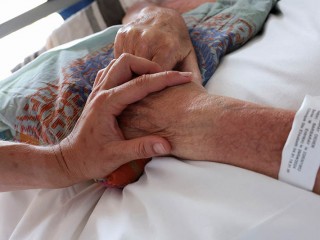 Một y tá chạm vào tay bệnh nhân tại khoa chăm sóc giảm nhẹ của một phòng khám ở Marseille, Pháp, ngày 31 tháng 5 năm 2024. Hội đồng giám mục Uruguay đã bày tỏ sự buồn bã vào ngày 13 tháng 8 năm 2025 sau khi Hạ viện nước này thông qua dự luật hợp pháp hóa an tử (Ảnh: OSV News/ Manon Cruz, Reuters)