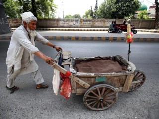 Một người bán hàng rong lớn tuổi đẩy chiếc xe gỗ của mình trên lề đường ở Peshawar, Pakistan (Ảnh: ANSA)