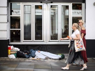 Mọi người đi ngang qua một người đang nằm nghỉ trên vỉa hè dọc theo một con phố ở London vào ngày 28 tháng 7 năm 2026 (Ảnh: Vatican News)