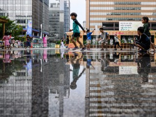 Trẻ em vui chơi giữa các đài phun nước trên một con phố ở Seoul vào ngày 14 tháng 8 năm 2024, trong đợt nắng nóng kéo dài đang bao trùm phần lớn đất nước (Ảnh: ANTHONY WALLACE / AFP)
