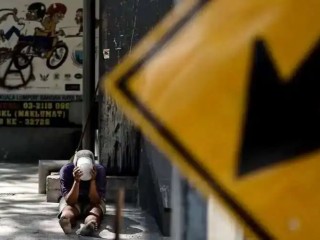 Một người đàn ông vô gia cư tại Malaysia đang ăn xin dưới chân một cây cầu dành cho người đi bộ ở Kuala Lumpur (Ảnh: AFP)